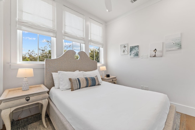 bedroom featuring ceiling fan, multiple windows, hardwood / wood-style flooring, and crown molding