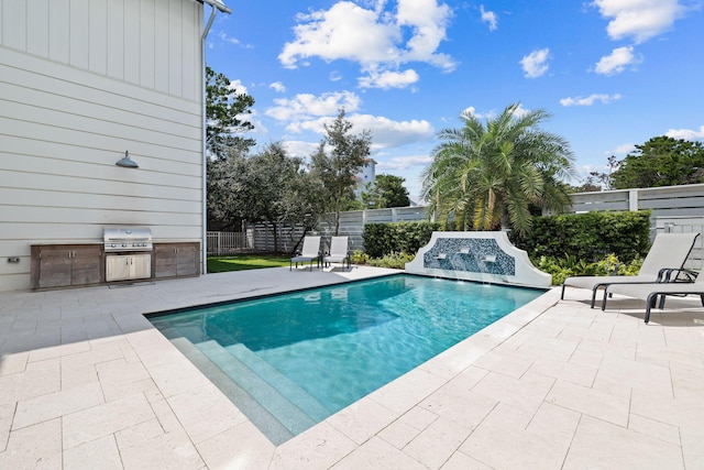 view of pool with exterior kitchen, a patio area, and area for grilling