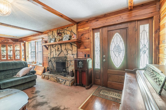 entryway with beam ceiling, a textured ceiling, wood walls, a fireplace, and wood-type flooring