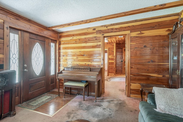 foyer with beam ceiling, wood walls, hardwood / wood-style floors, and a textured ceiling