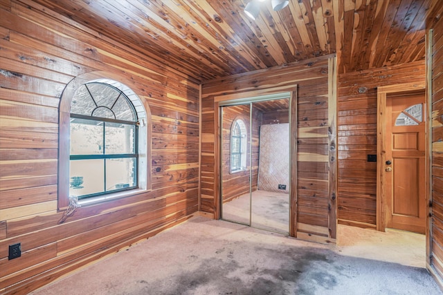 unfurnished bedroom featuring wood walls, multiple windows, and wooden ceiling