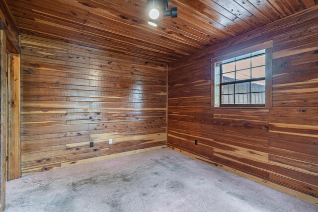 carpeted spare room featuring wood ceiling and wooden walls