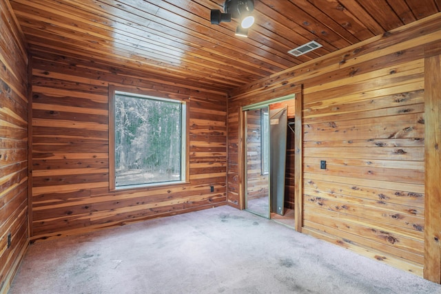 empty room with wood walls, carpet, and wood ceiling