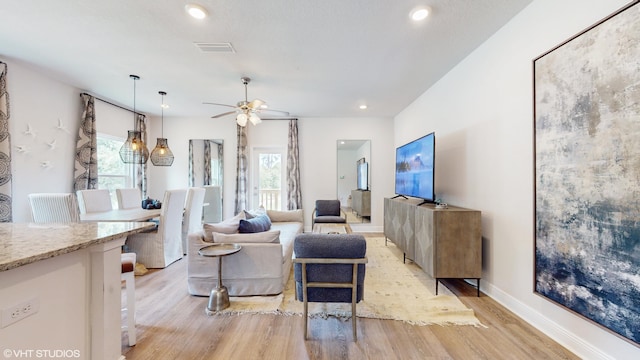 living room with light hardwood / wood-style floors, a wealth of natural light, and ceiling fan