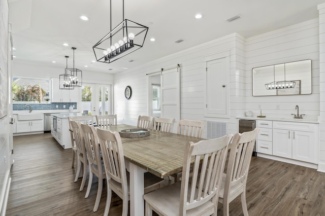 dining space featuring recessed lighting, visible vents, a barn door, dark wood-type flooring, and wood walls