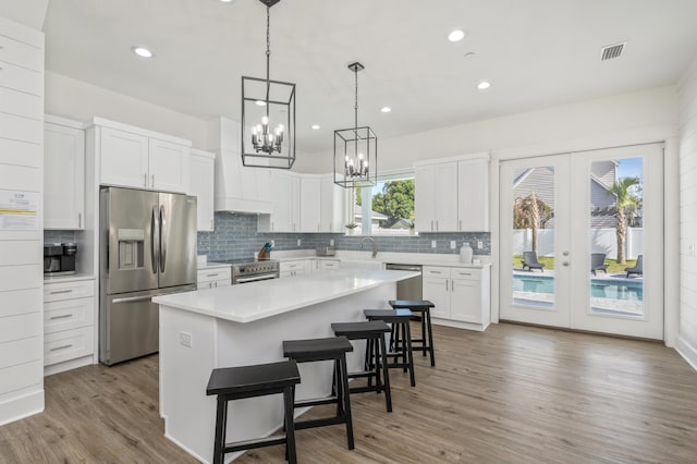 kitchen with light countertops, visible vents, appliances with stainless steel finishes, white cabinetry, and a kitchen island