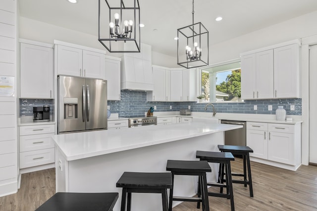 kitchen with stainless steel appliances, light countertops, premium range hood, and white cabinetry