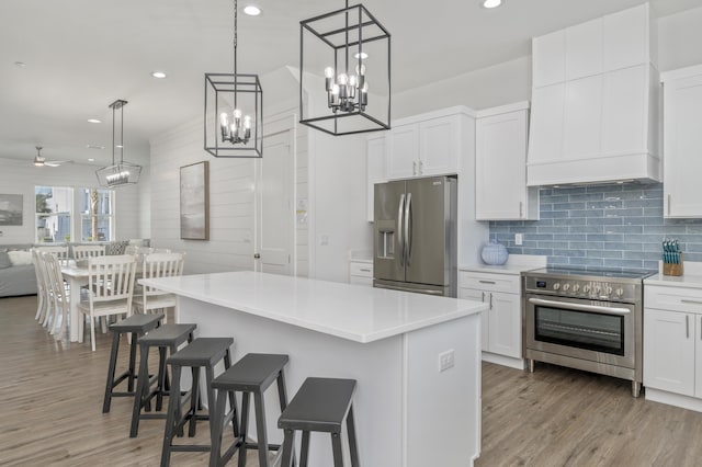 kitchen with white cabinets, appliances with stainless steel finishes, open floor plan, a center island, and light countertops