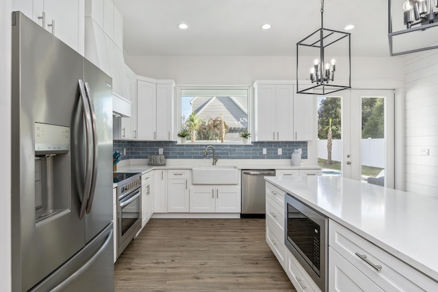 kitchen with a sink, stainless steel appliances, light countertops, and white cabinets