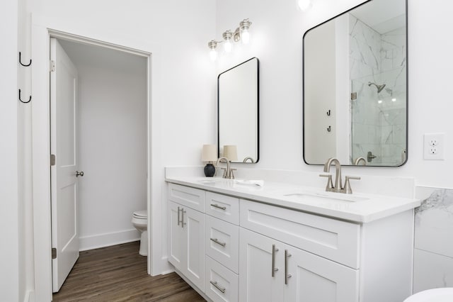 bathroom featuring wood finished floors, a sink, toilet, and double vanity