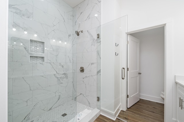 full bathroom with toilet, a stall shower, vanity, wood finished floors, and baseboards