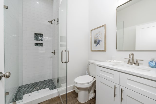 bathroom featuring vanity, a stall shower, wood finished floors, and toilet