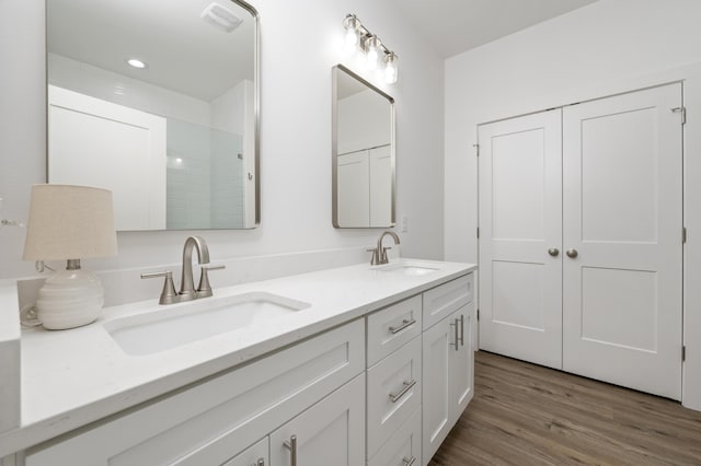 bathroom with double vanity, visible vents, a sink, and wood finished floors