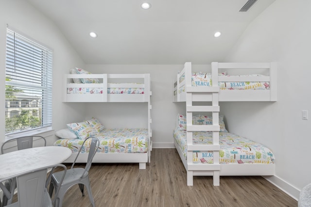 bedroom featuring lofted ceiling, baseboards, visible vents, and wood finished floors