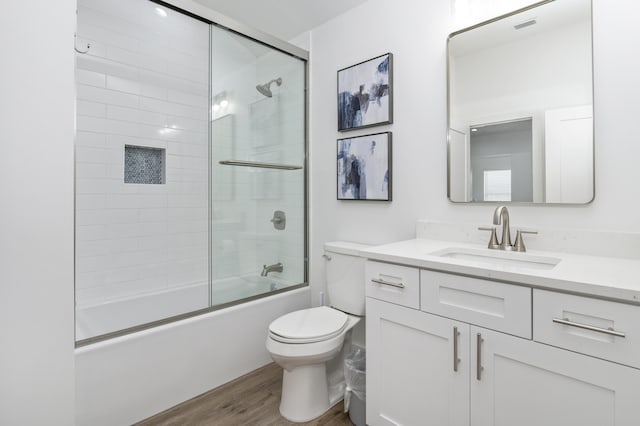 full bathroom featuring toilet, bath / shower combo with glass door, wood finished floors, visible vents, and vanity