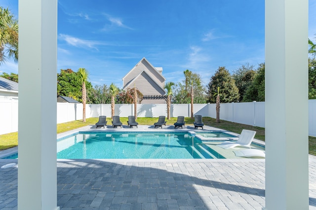 view of swimming pool featuring a pool with connected hot tub, a fenced backyard, and a patio