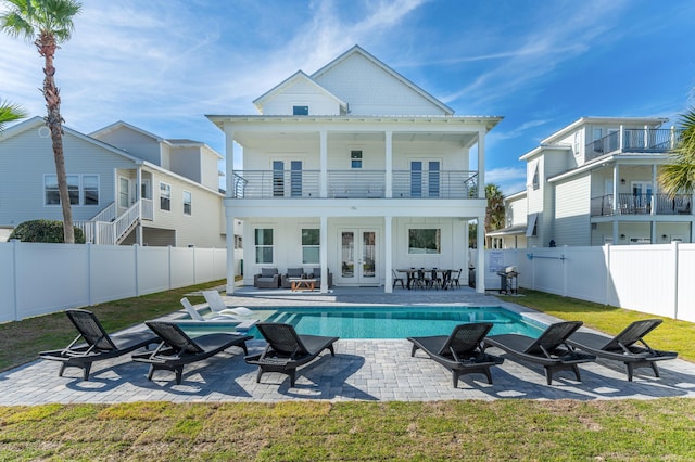 rear view of house featuring a fenced backyard, a balcony, french doors, a fenced in pool, and board and batten siding