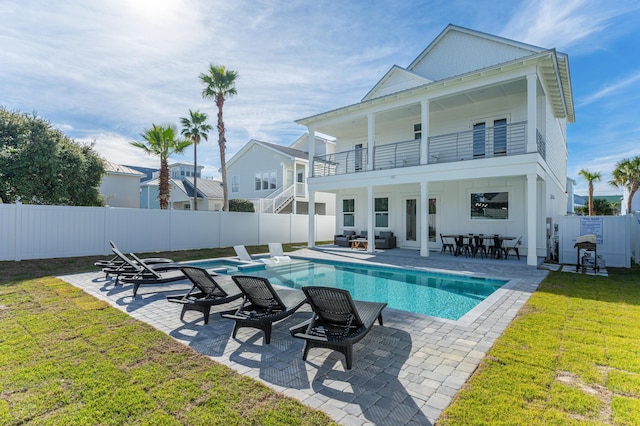 rear view of property with a fenced in pool, board and batten siding, a patio area, a balcony, and a fenced backyard