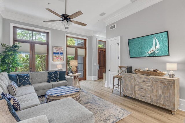 living room with ornamental molding, french doors, ceiling fan, and light wood-type flooring