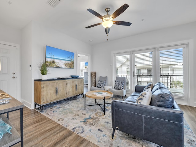 living area with a ceiling fan, baseboards, visible vents, and wood finished floors