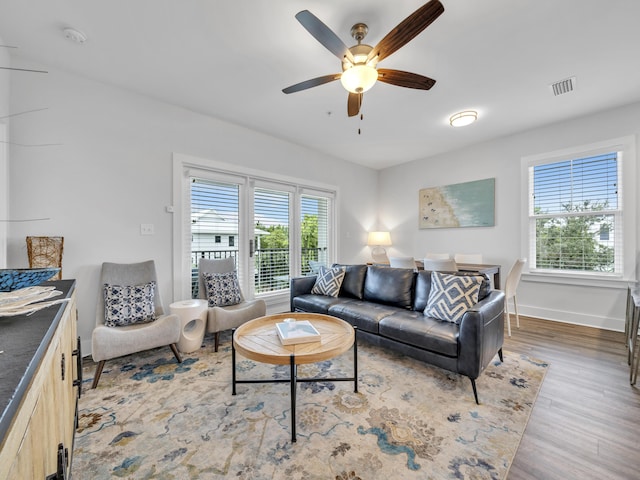 living area with a ceiling fan, baseboards, visible vents, and wood finished floors