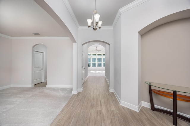 hallway with light wood-type flooring, an inviting chandelier, and ornamental molding