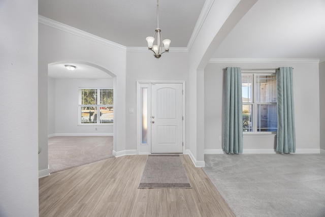 foyer featuring ornamental molding, light colored carpet, an inviting chandelier, and a wealth of natural light