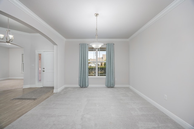 carpeted empty room with ornamental molding and an inviting chandelier