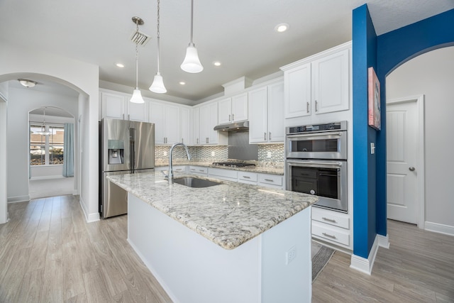 kitchen with stainless steel appliances, a center island with sink, and white cabinetry