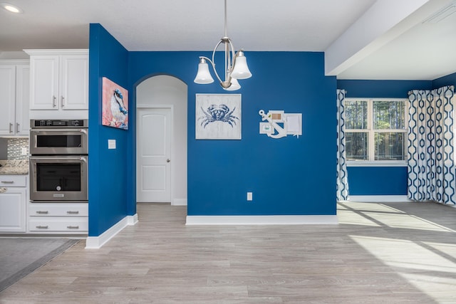 kitchen with decorative light fixtures, white cabinets, light hardwood / wood-style flooring, and decorative backsplash