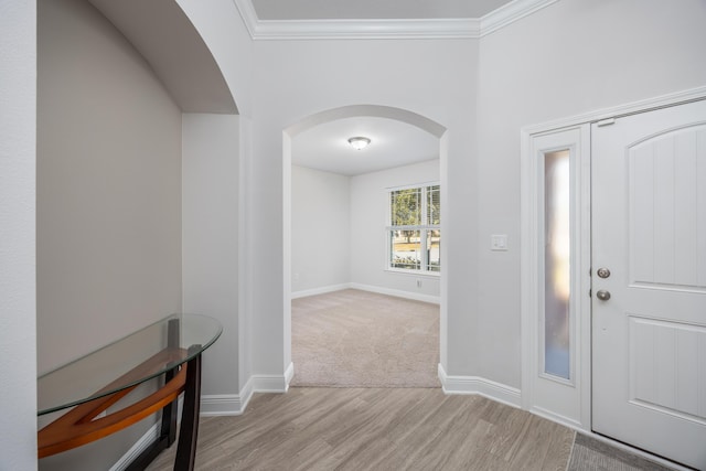 entryway with ornamental molding and light hardwood / wood-style floors