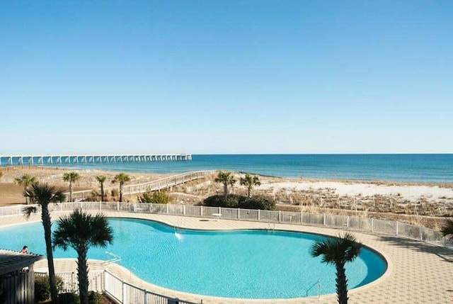 community pool featuring a patio area, a water view, and fence