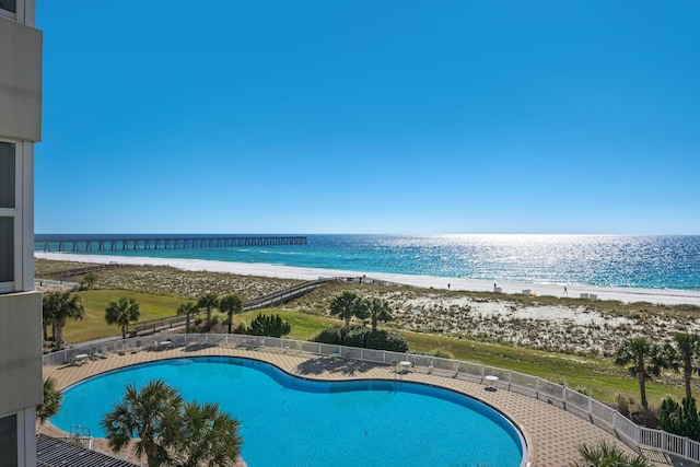 pool featuring fence, a beach view, and a water view