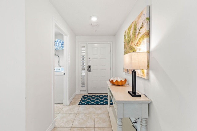 foyer entrance with light tile patterned floors, washer / clothes dryer, and baseboards