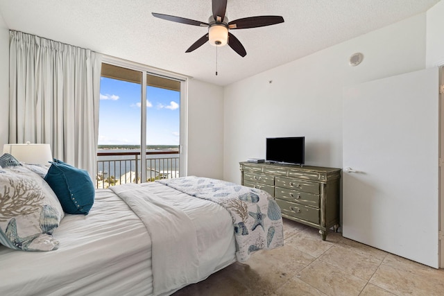 bedroom with a wall of windows, a textured ceiling, access to exterior, and a ceiling fan