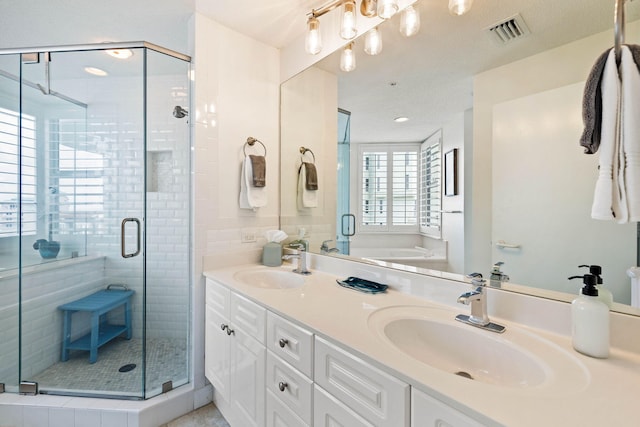 bathroom featuring double vanity, visible vents, a stall shower, and a sink