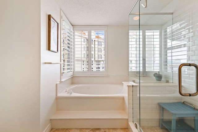 full bath with a textured ceiling, a stall shower, and a bath