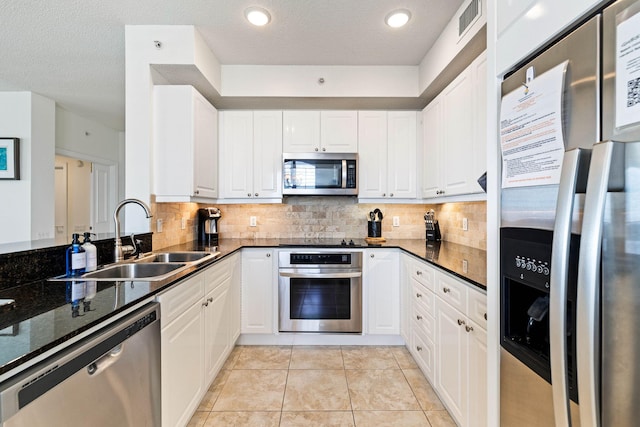 kitchen with tasteful backsplash, appliances with stainless steel finishes, white cabinetry, and a sink