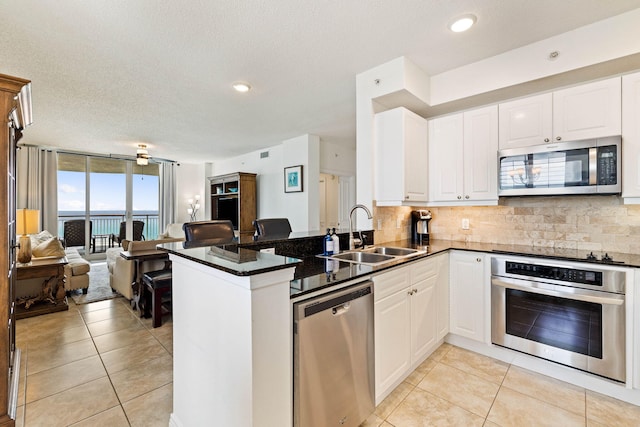 kitchen with a sink, tasteful backsplash, open floor plan, stainless steel appliances, and a peninsula