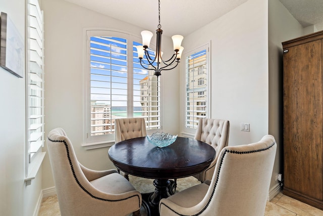 dining space featuring light tile patterned floors, baseboards, and a chandelier