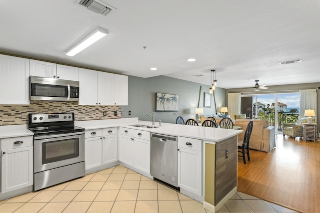 kitchen featuring visible vents, light countertops, appliances with stainless steel finishes, a sink, and a peninsula