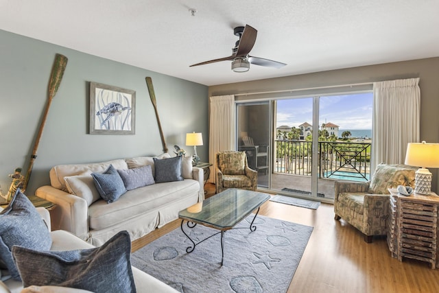 living room featuring a textured ceiling, light wood-type flooring, and a ceiling fan