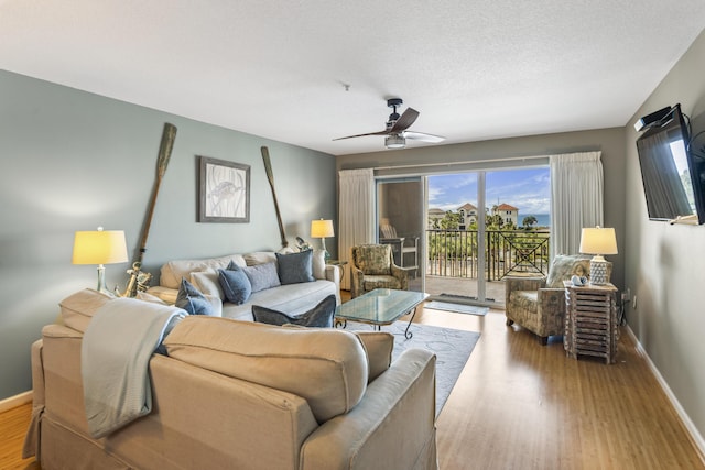 living area featuring a textured ceiling, baseboards, and wood finished floors