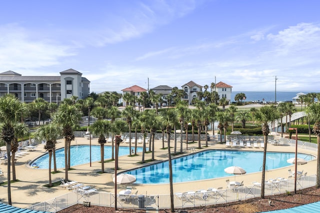 community pool with a patio area and fence