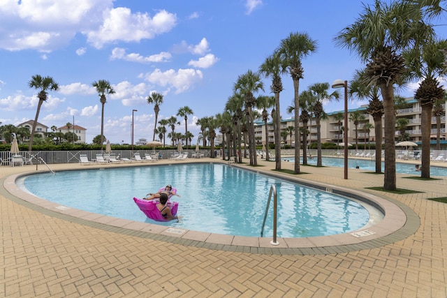 pool with a patio area and fence