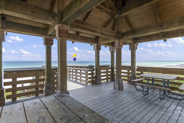 wooden deck with a water view, a beach view, and a gazebo