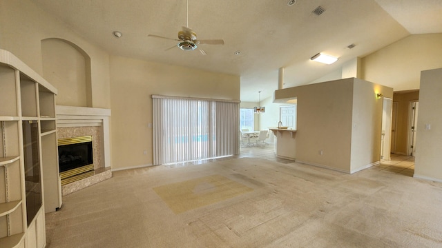 unfurnished living room with ceiling fan, light colored carpet, a high end fireplace, and high vaulted ceiling