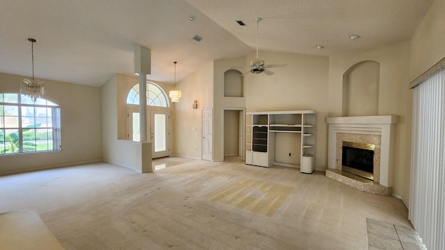 unfurnished living room with ceiling fan with notable chandelier, a fireplace, light colored carpet, and high vaulted ceiling