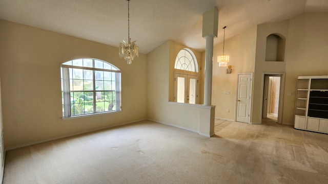 empty room with a notable chandelier, light colored carpet, and high vaulted ceiling