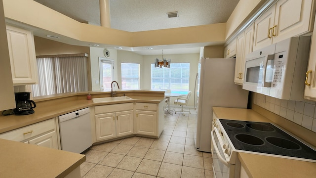 kitchen with a notable chandelier, light tile patterned floors, white appliances, sink, and kitchen peninsula